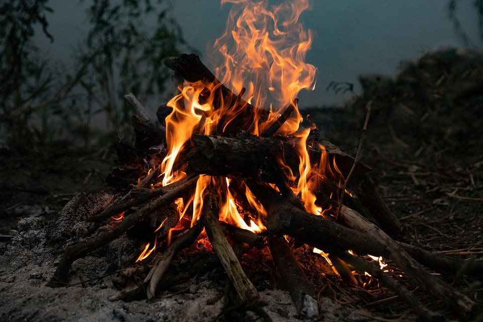 Campfire burning outdoors during emergency fire-starting preparation