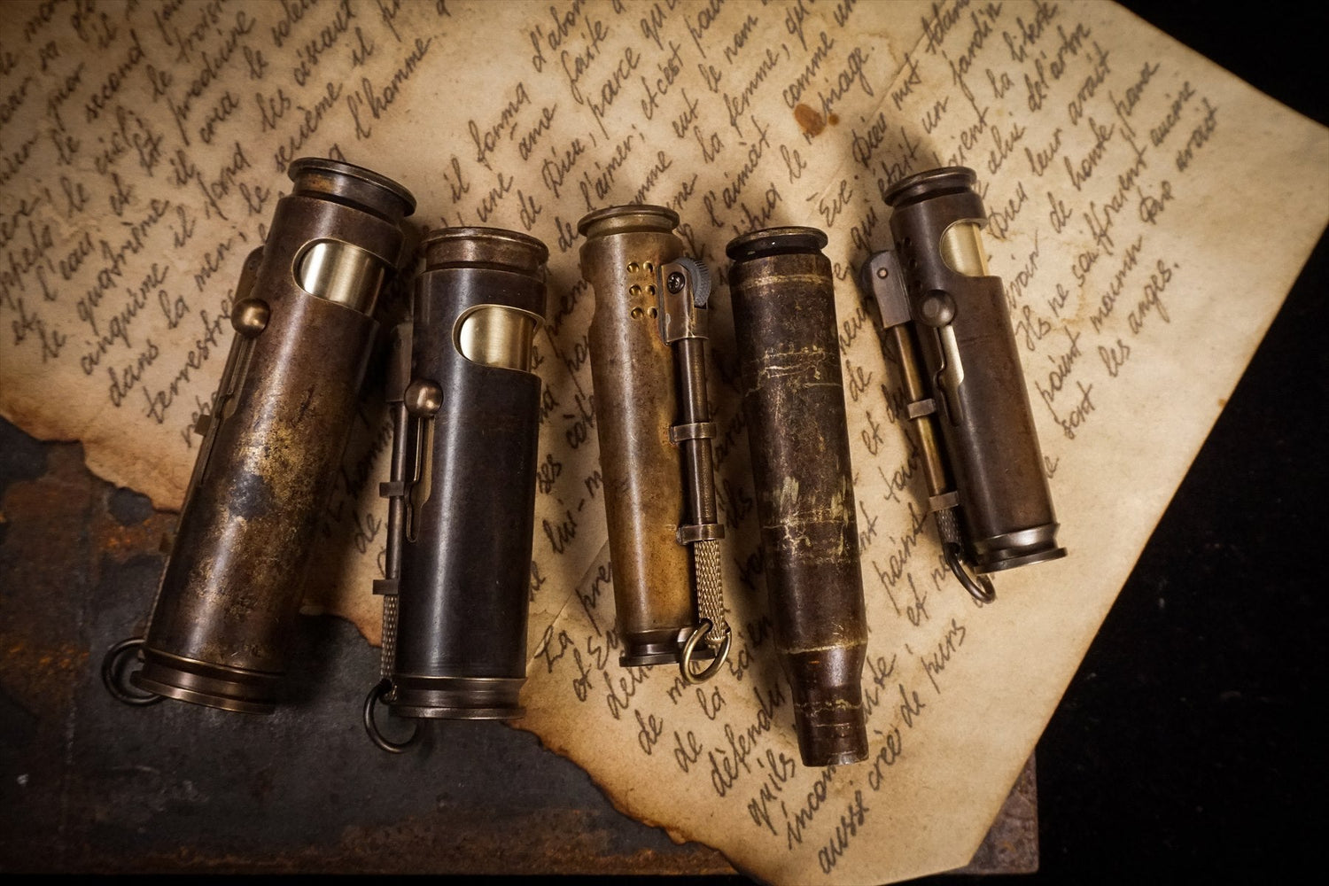 Several modern aged-brass WEDO lighters arranged on a distressed handwritten page