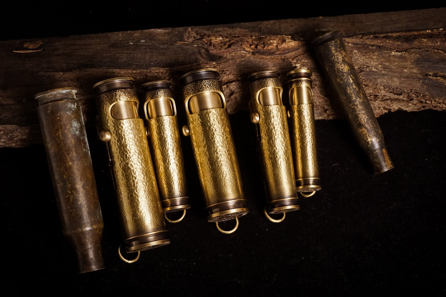 Real hammered brass shell lighters arranged on dark workshop wood