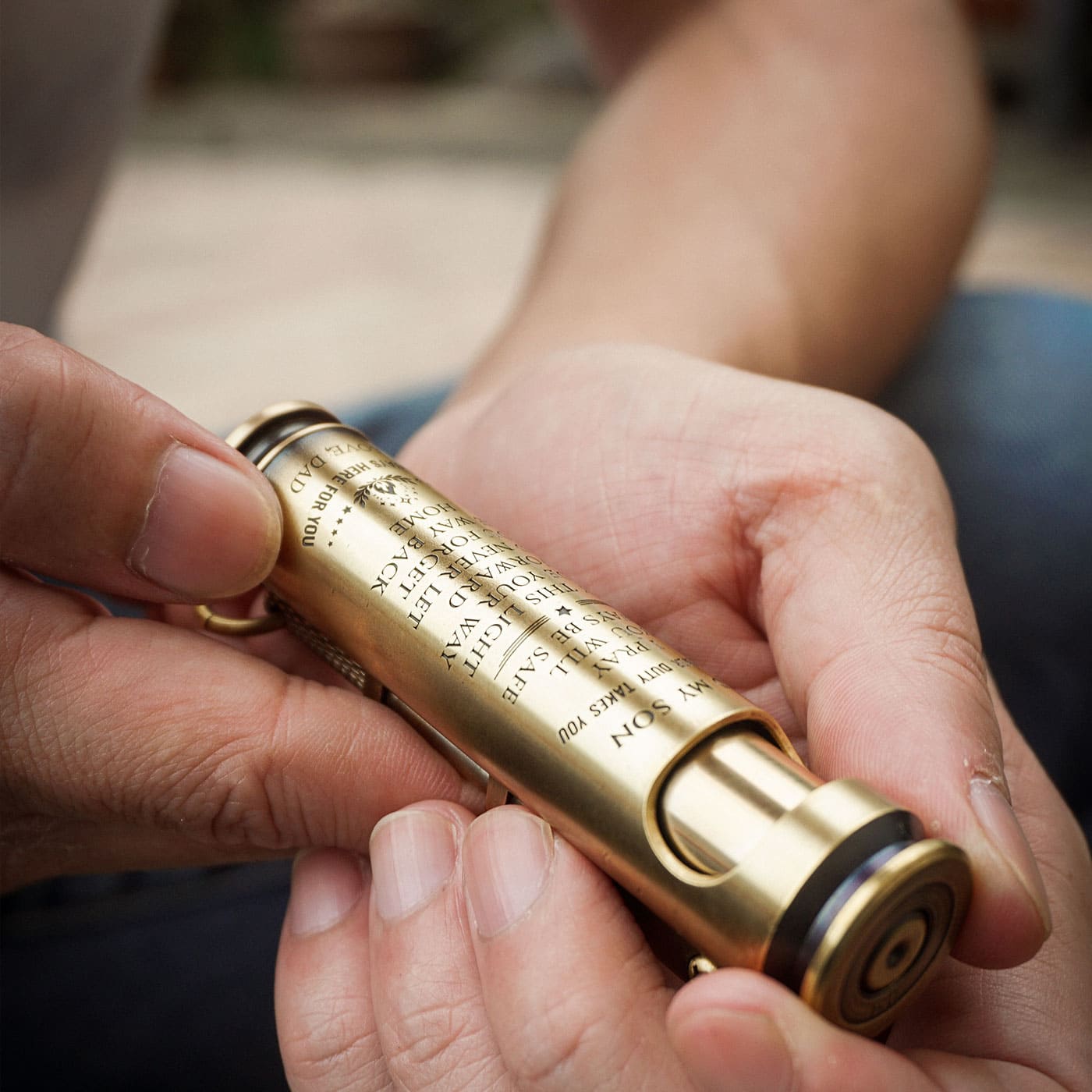 Custom engraved brass lighter held in hands with personalized text